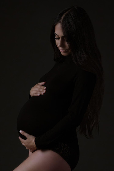 Close-up of expectant mother in black, holding belly